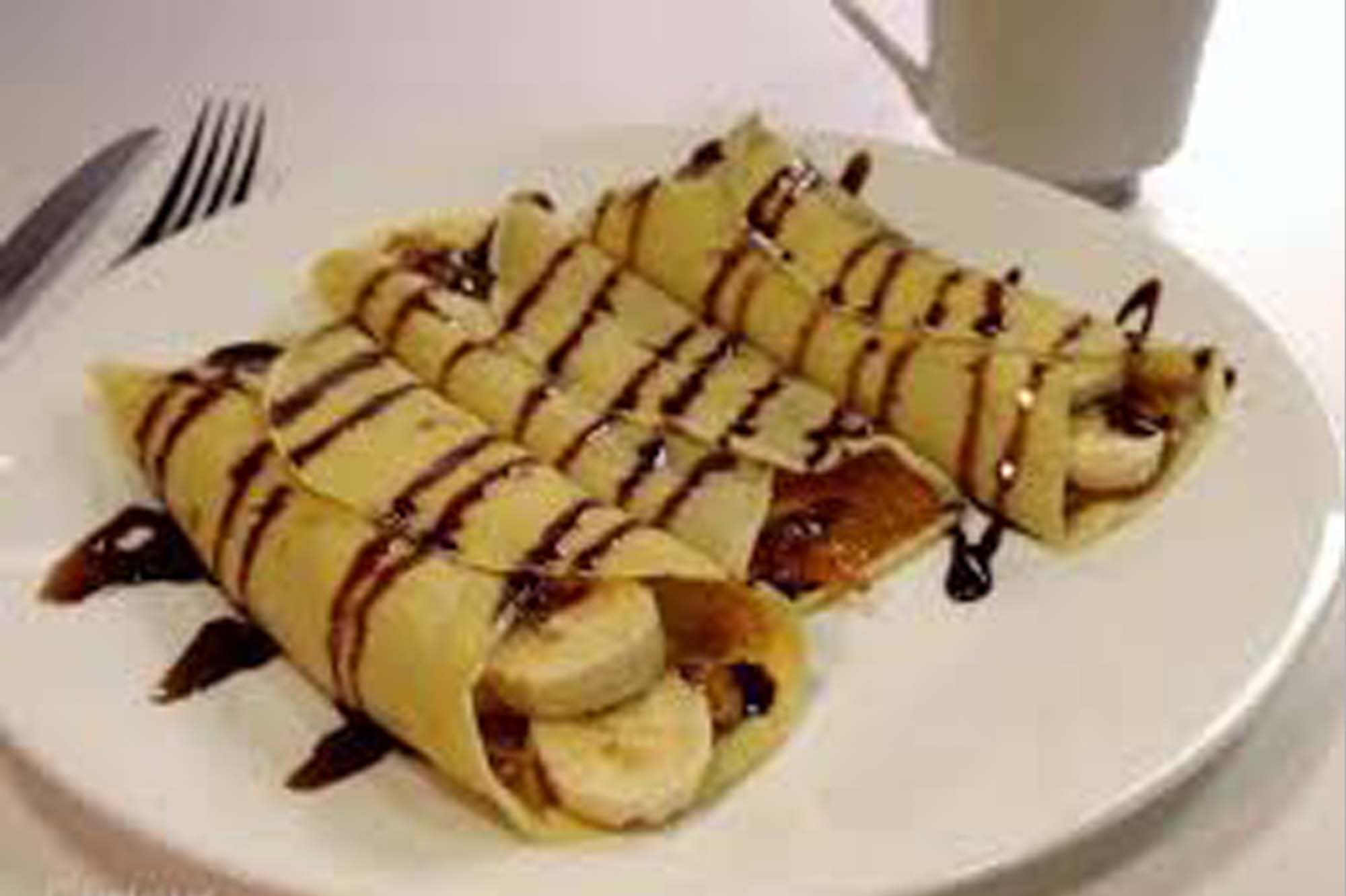 picture of french crepes, with banana pieces inside and drizzled in chocolate.